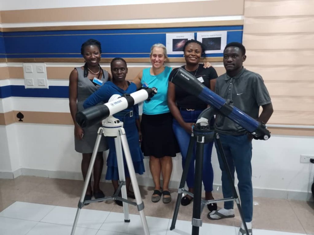 Dr. Linda Strubbe with a group of students standing beside two telescopes.