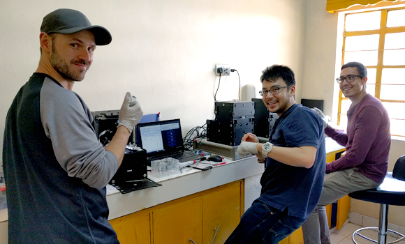 Christian Fobel, Alphonsus Ng, and Julian Lamanna running blood tests on the MR box instruments in their temporary lab in one of the Kakuma health clinics.