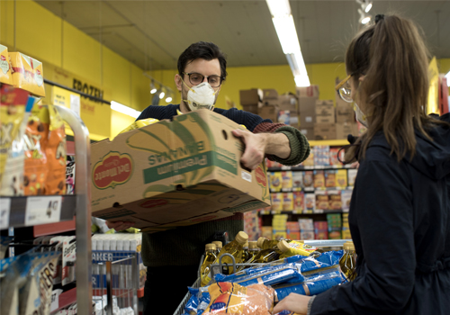 Adam Zivo in an N-95 mask holding a banana box in a grocery store.