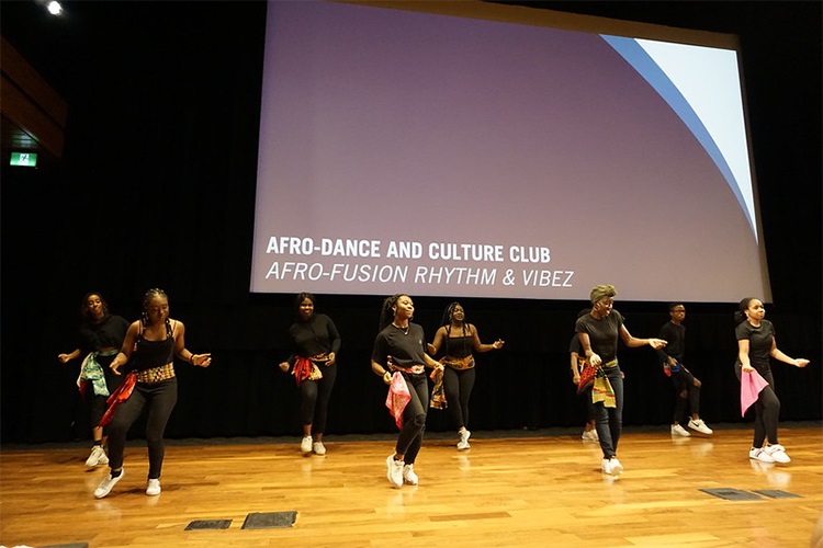 Photo of 9 people dancing in front of a screen