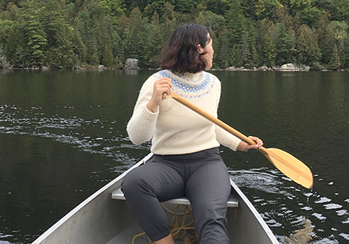 Alexandra Gaspar in a canoe looking back at a green trees.