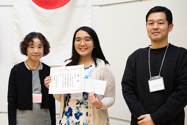 Annie Liu holding her third prize award flanked between judges