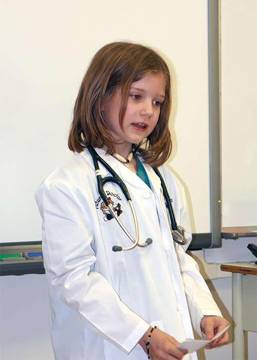 Annika Waschke -- dressed in a white lab coat with a stethoscope around her neck --explaining to her Grade 3 class that her dream is to one day be a doctor   