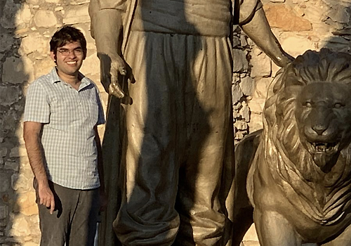 Arshan Hasan standing beside a large statue of a lion.