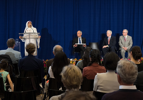 Aisha Ahmad, stands on stage in front of a large crowd to accept the Northrop Frye Award for faculty.