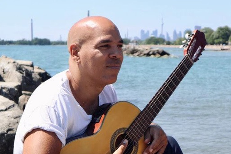 Beau Dixon on a beach with a guitar