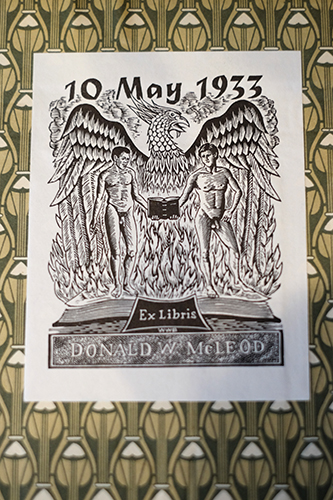 A bookplate with a phoenix and two men holding a book dated 10, May 1933.