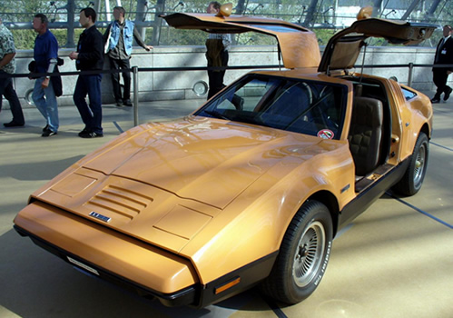 A yellow Bricklin with gull-wing doors open at a car show