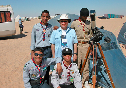Ralph Chou and four boy scouts stand outside beside a telescope on a sunny day.