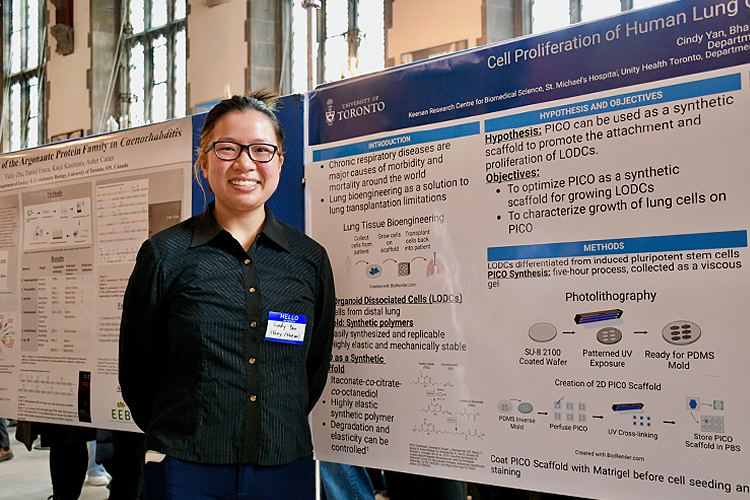 Cindy Yan standing in front of posters for their research.