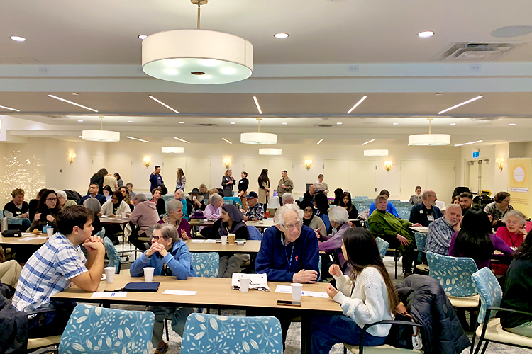 A classroom full of people at tables chatting.