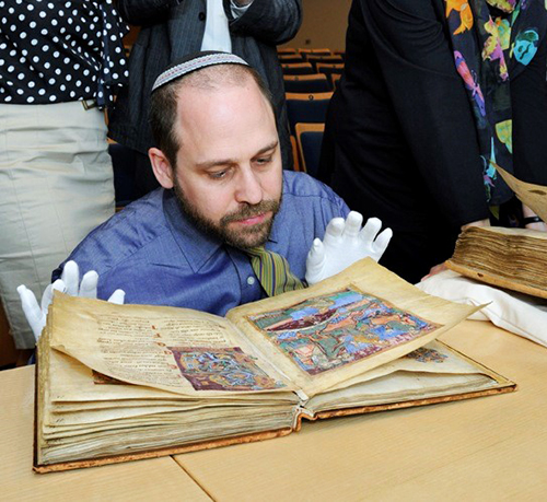 Adam S. Cohen seated looking intently at an ancient book