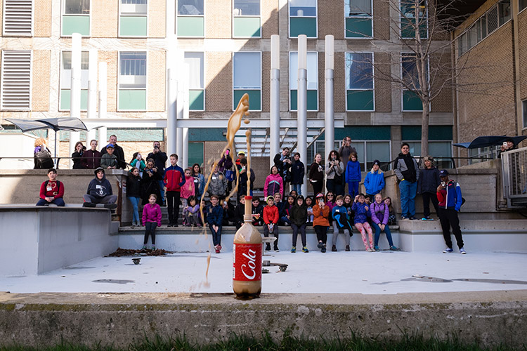 Students watch a bottle of cola explode during a chemistry demonstration.