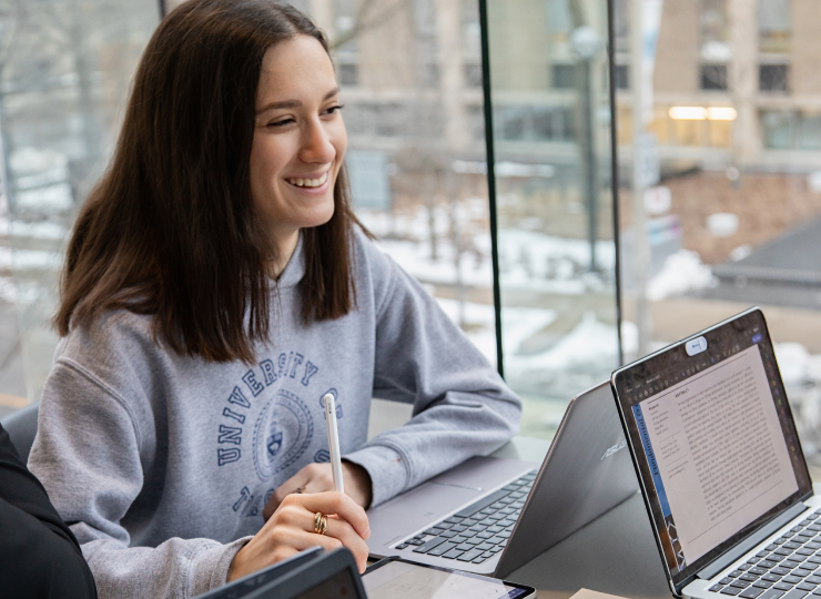 Student smiling and sitting in front of a computer