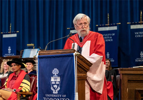 David Andrews standing on stage inside Convocation Hall.