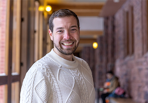 David Kepes standing inside of Munk School of Global Affairs &amp; Public Policy.