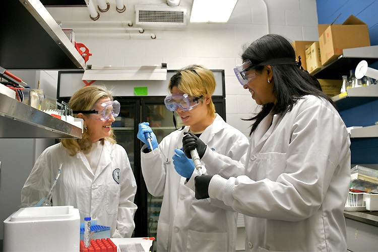 Dean Melanie Woodin in her lab with 2 students