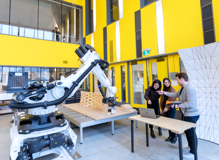 Three people in a yellow room with a large robot.