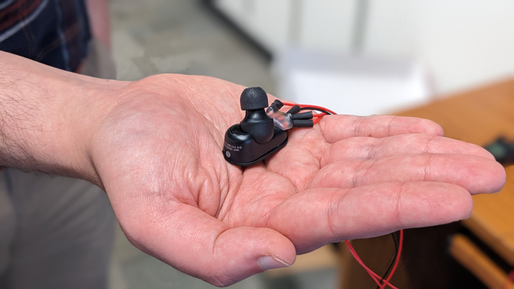 A close up of hand with an earbud in the palm