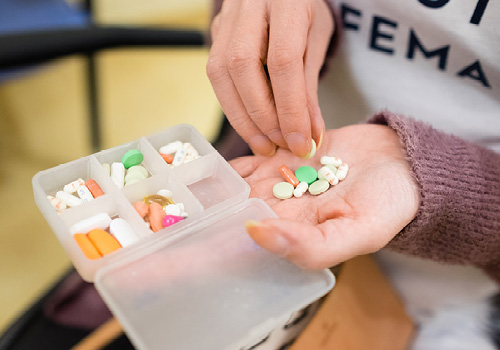 A close-up of Elspeth Arbow's hand, which has a small pile of colourful pills in it