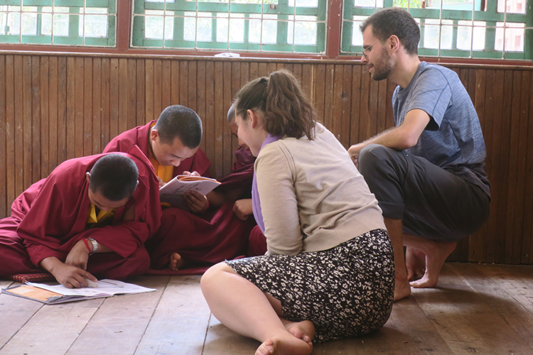Students sitting with young monks while they read books