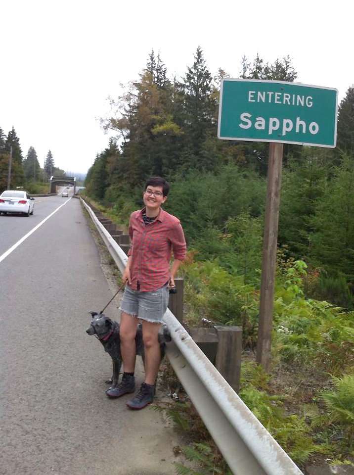 Sarah Dowling in front of a roadsign saying Entering Sappho