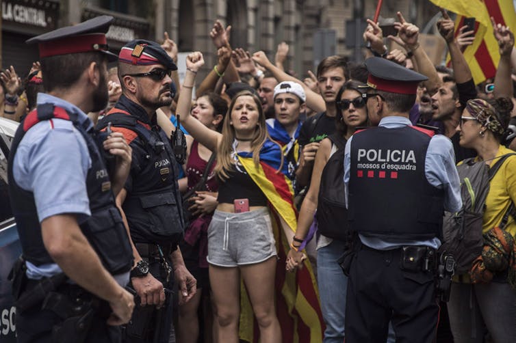 Catalan regional police officers stand between protesters and national police headquarters