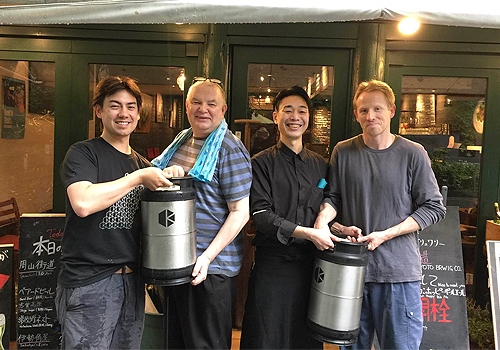 Paul Speed and Chris Hainge standing in an Irish pub with two pub staff in Tokyo.