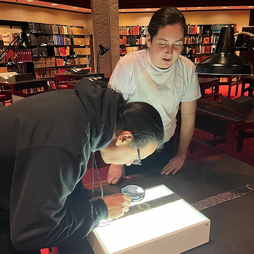 Alan Corbiere and Mikinaak Migwans observing a book.