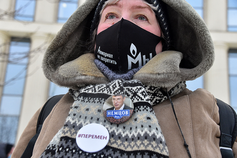 A woman wearing a face mask with the logo of Russia's rights group Memorial is seen outside the Moscow City Court