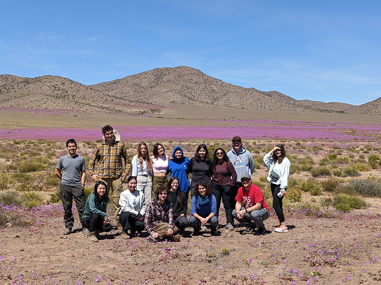 a group of students standing in field of flowers