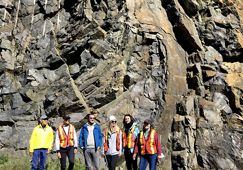 A group of students in front of a rock wall.