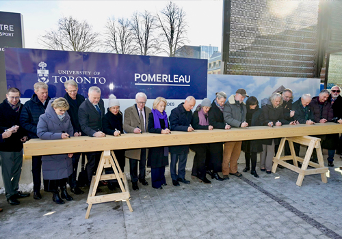 A group of people signing a large piece of wood.
