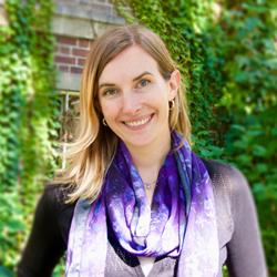 Gwen Eadie poses in front of vine covered brick walls.