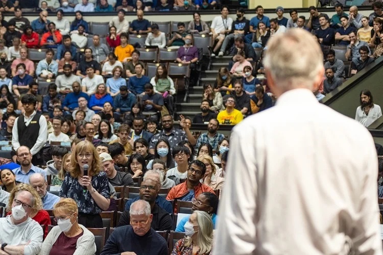 Hinton speaking before a large crowd at Con Hall