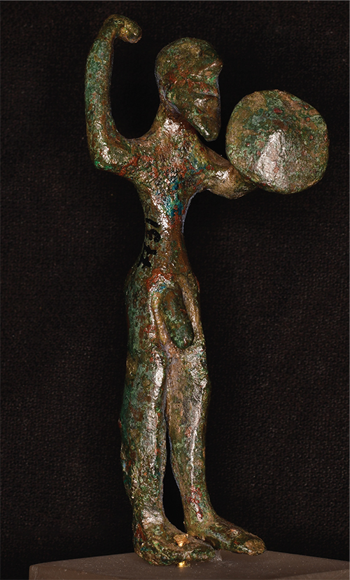 A bronze figurine of a nude warrior holding a shield