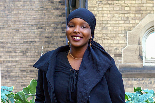 Ikran Jama standing in front of a building on the U of T campus