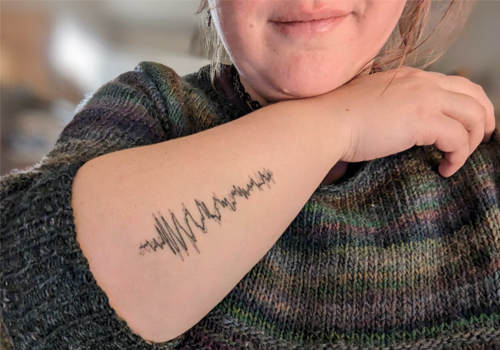 A tattoo on a forearm with a black zig-zagged line.