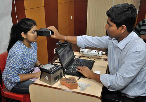 A man holds up a device in front of a woman's face to collect biometric data
