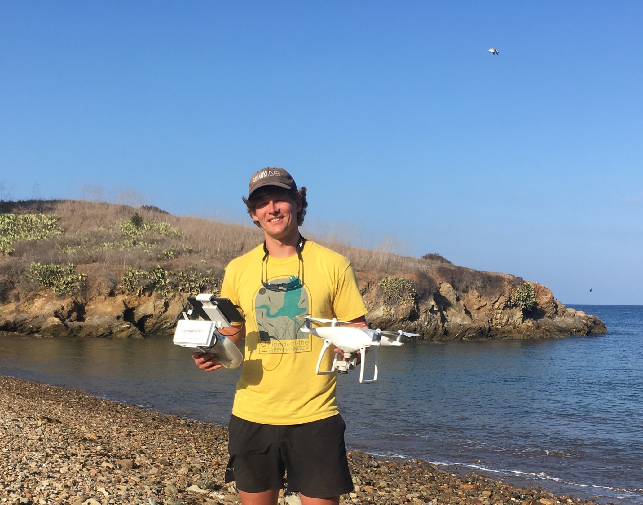 Jack May holding two drones on a rocky beach