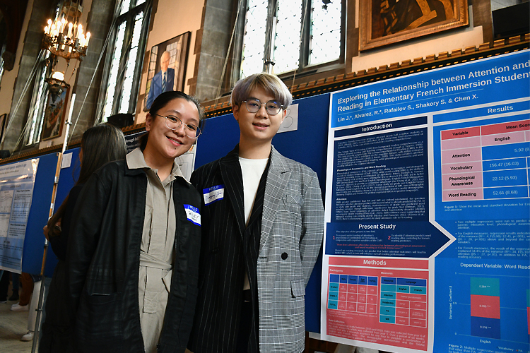 Riley Alvarez, Trinity College & Jianyuan Li, Victoria College standing in front of posters for their research.