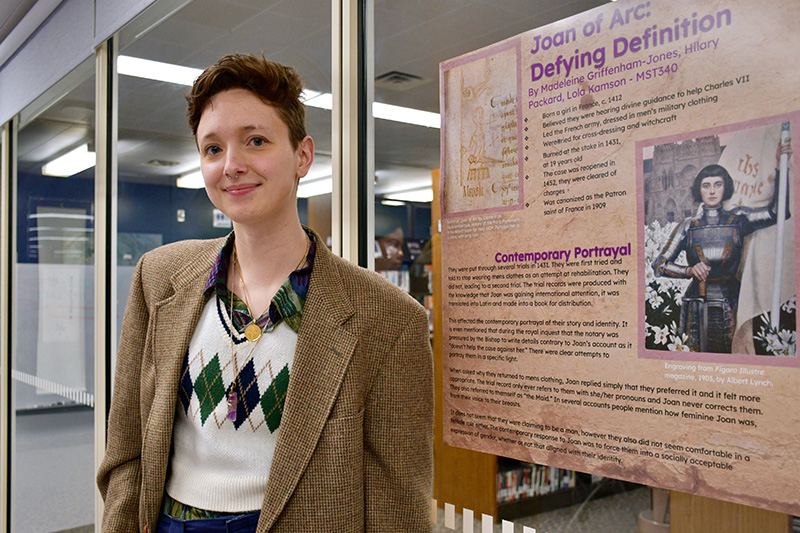 A student standing in front of a research poster