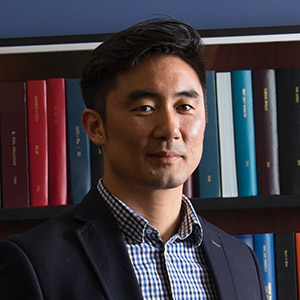 Jooyoung Lee, an associate professor of sociology, standing in-front of books.