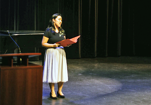 Georgia Lin standing on a large stage performing.