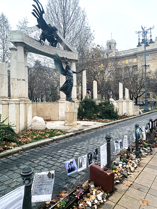 A memorial with pictures hanging on a fence and a statue of an angel.