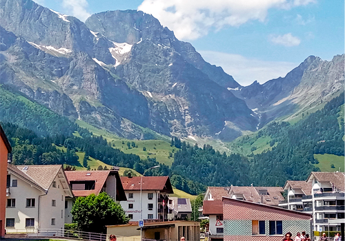 Buildings in Locano Switzerland and large mountains in the background under a bright blue sky.