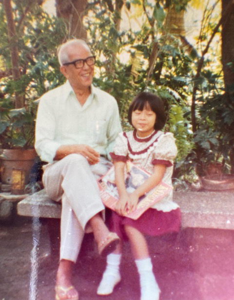 Shelley Lumba  as a child sitting with her grandfather on a bench outdoors