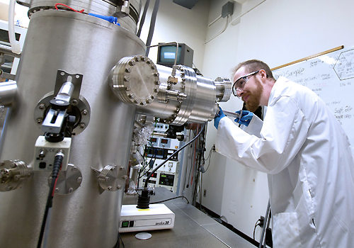 Matthew Timm looking into a microscope in lab.