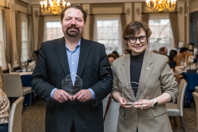 Oksana Dudko and Michal Mlynarz holding glass awards.