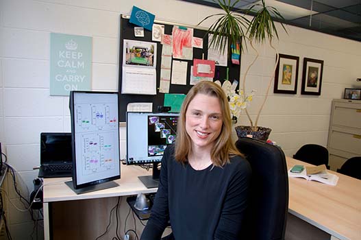 Morgan Barense sitting at her desk with an illuminated computer screen behind her
